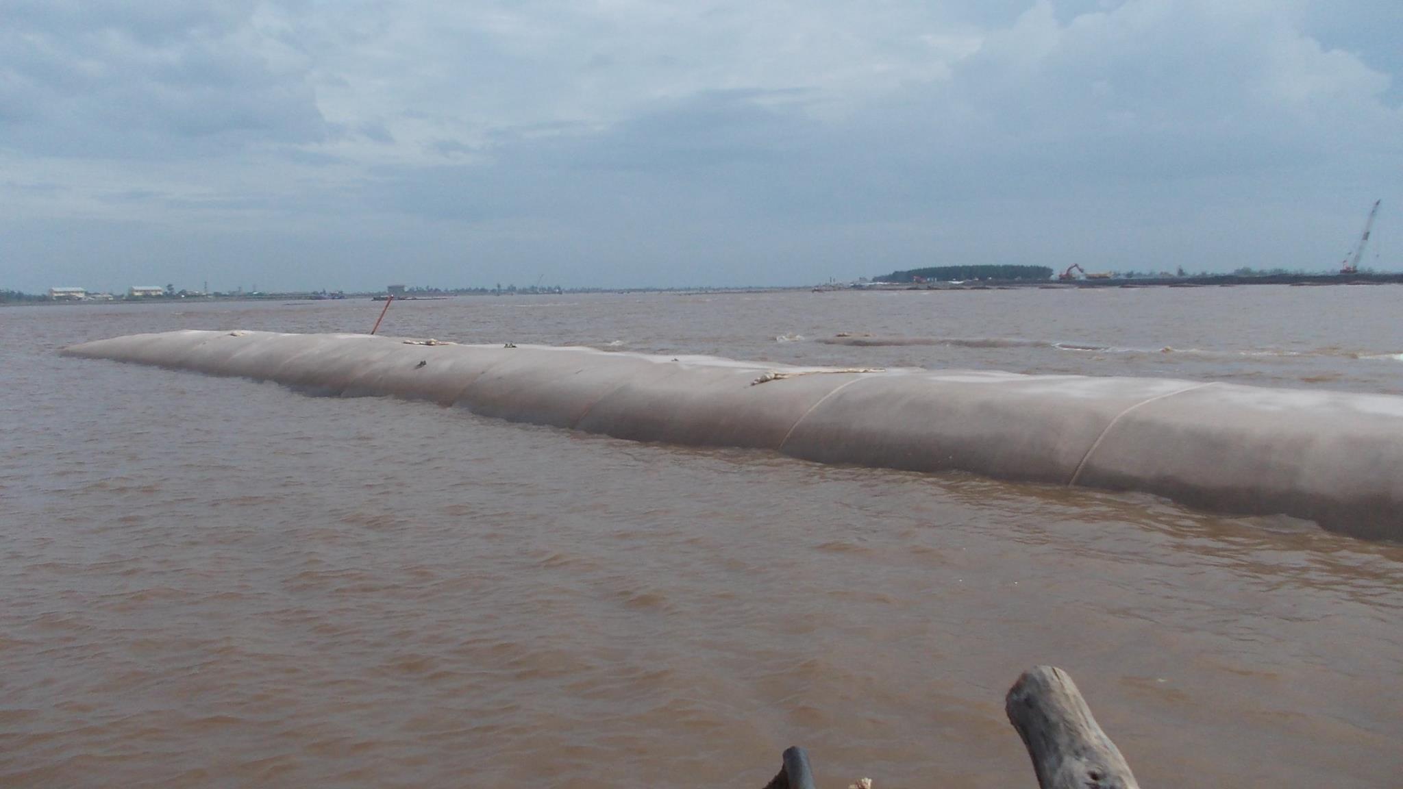 Hướng dẫn kỹ thuật lắp đặt ống địa kỹ thuật trong công trình đê chắn sóng, bao gồm việc quấn vải địa kỹ thuật quanh ống để ngăn chặn bùn cát