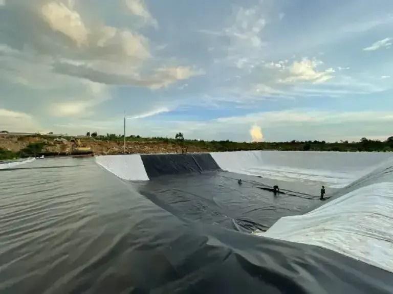 Hình ảnh công nhân đang triển khai thi công vải địa kỹ thuật 12kn/m trên nền đường cao tốc đang xây dựng, minh họa rõ nét việc ứng dụng vật liệu gia cố nền móng để tăng cường sự ổn định và khả năng chịu tải cho công trình giao thông.