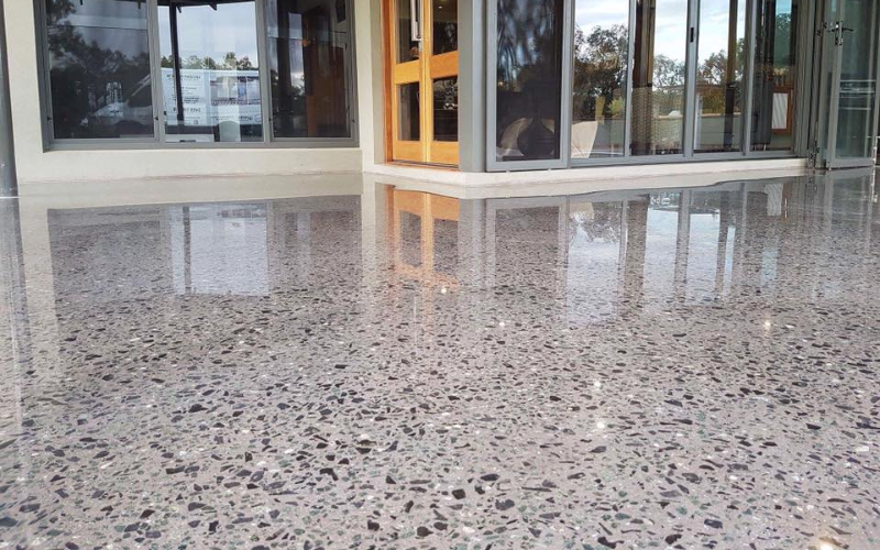 Một công nhân đang sử dụng máy mài công nghiệp để làm sạch và chuẩn bị bề mặt trần nhà bê tông trước khi áp dụng quy trình chống thấm.